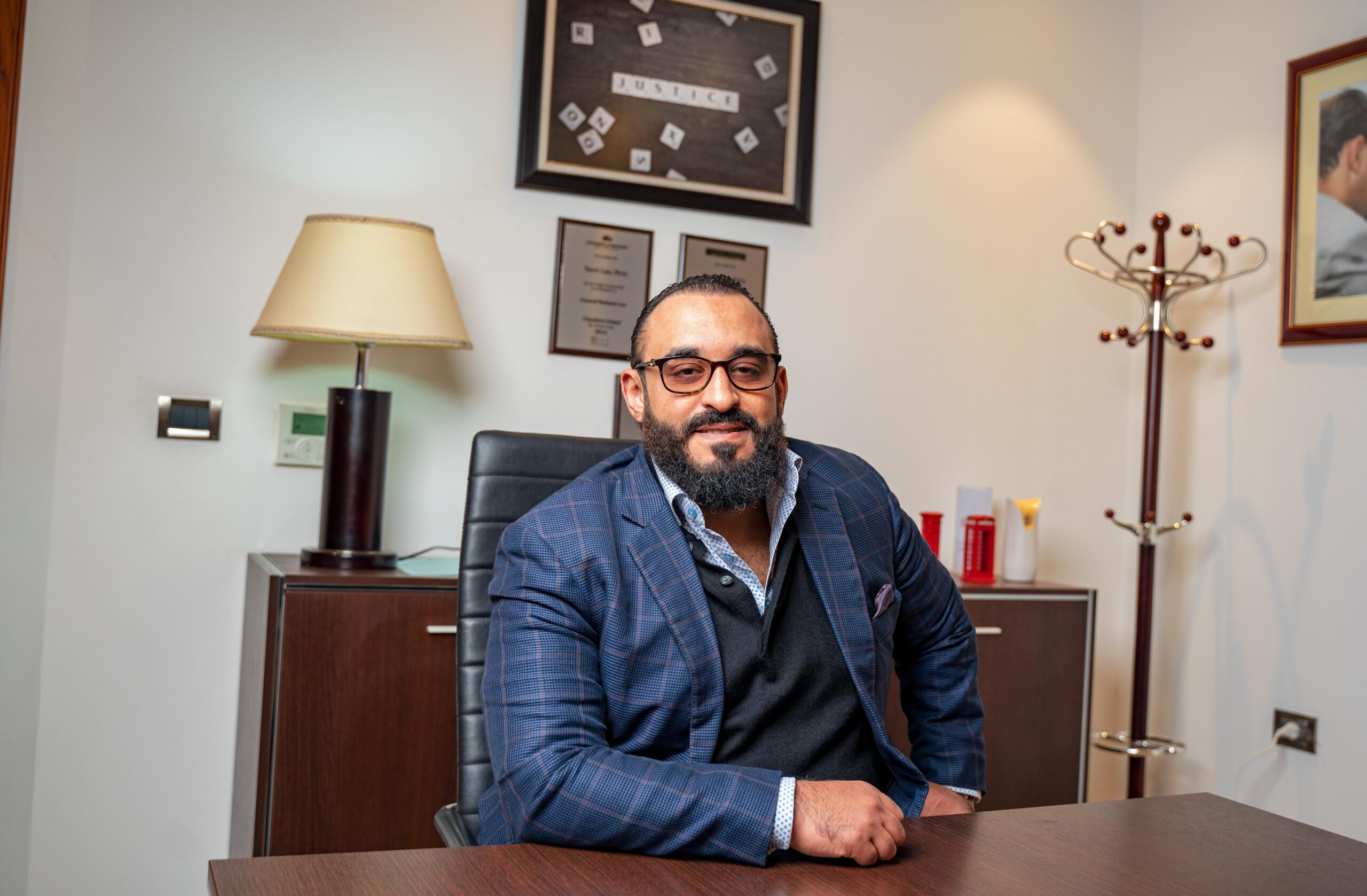 Bearded businessman in a suit seated at his office desk, exuding confidence.