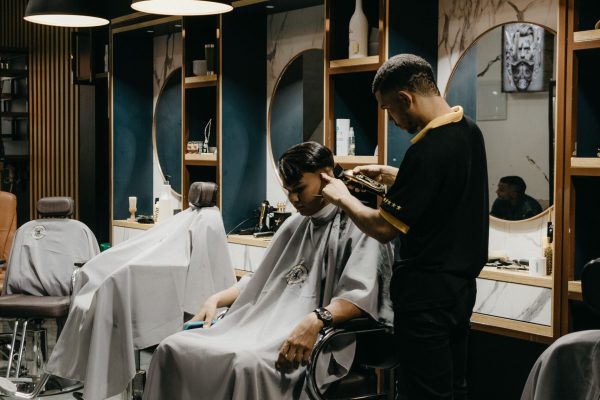 A professional barber giving a haircut to a client inside a stylish barbershop.