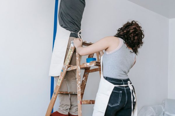 Couple working together on home renovation, painting walls in new apartment.