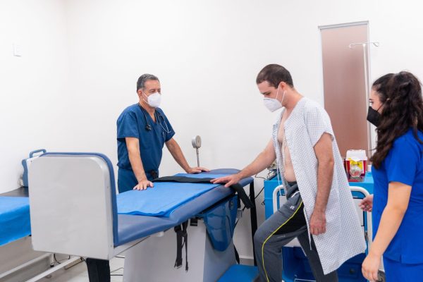 Patient undergoing medical examination assisted by healthcare professionals in a clinic.